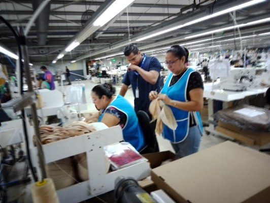 Team members inspecting garment components at a work table.