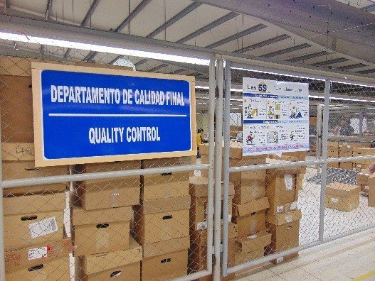 The final quality control department at the A&T Nicaragua plant, with cartons staged behind a signed and gated inspection area.
