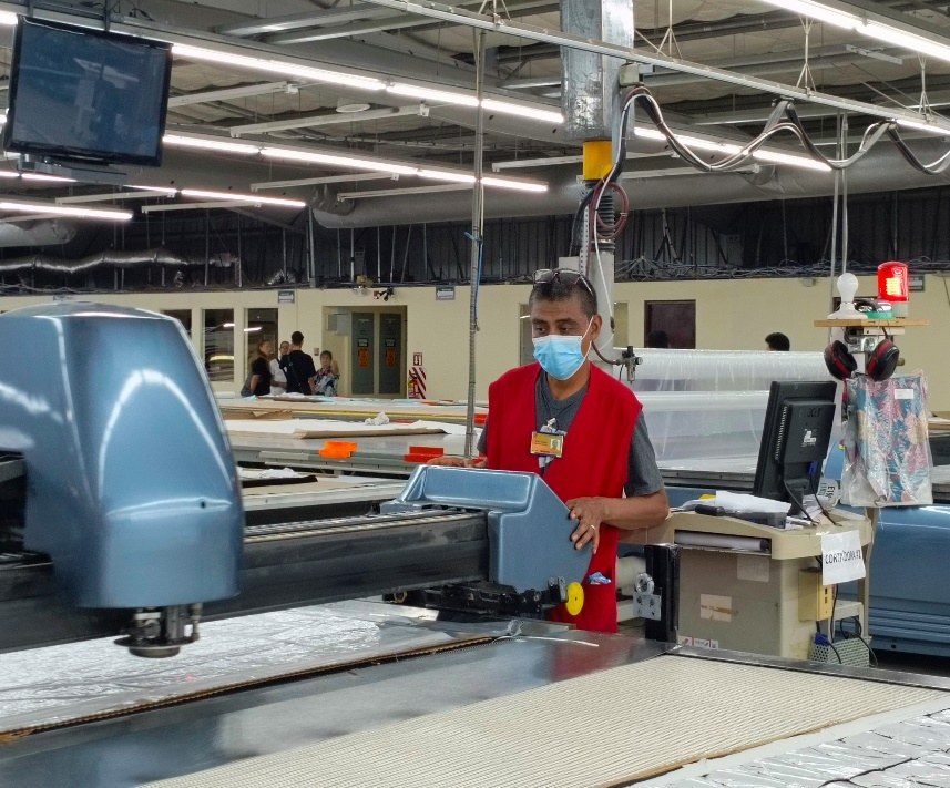 An operator running an automated fabric cutter on the cutting floor.