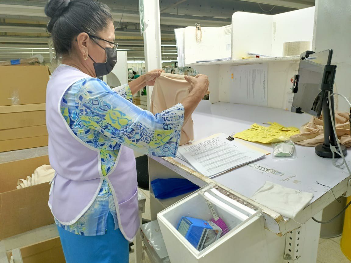 A quality auditor inspecting a finished garment at a final inspection station.