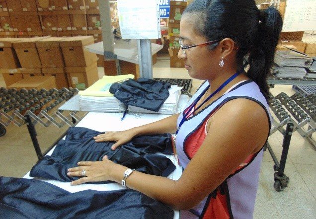 A team member folding and checking a finished dark garment at a work table.